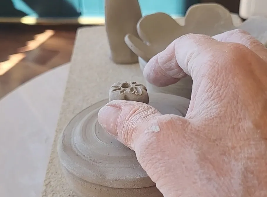 Hand formt Ton auf einer Töpferscheibe.