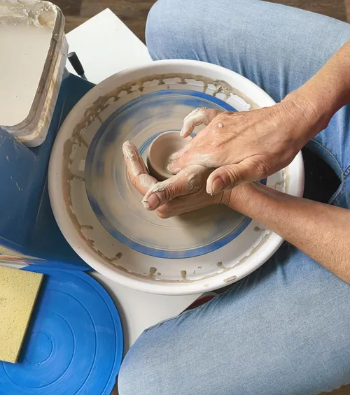 Hands shaping clay on a pottery wheel.
