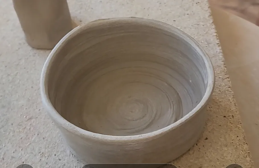 Unfired clay bowl on a textured surface.
