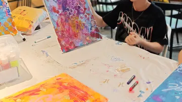 Child painting colorful abstract art at table.