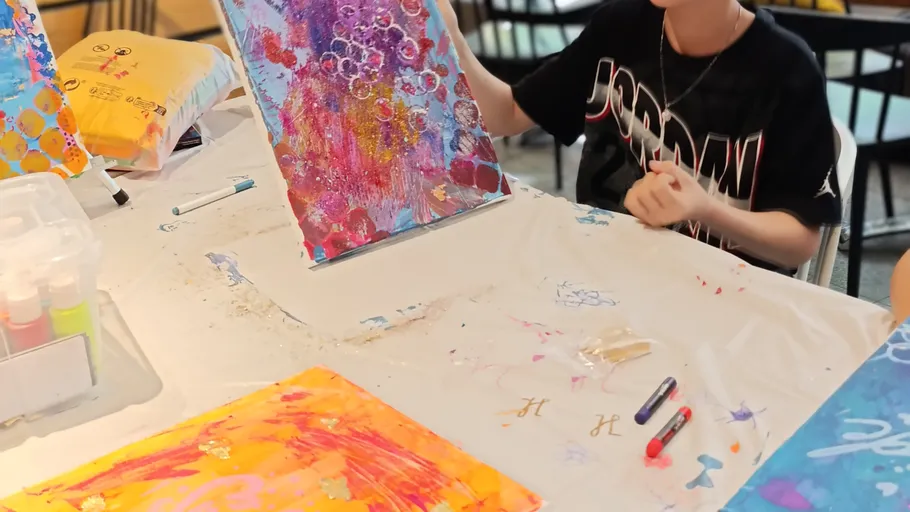Kind malt bunte abstrakte Kunst am Tisch.