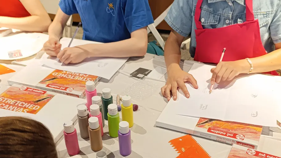 People drawing with pencils at a table.