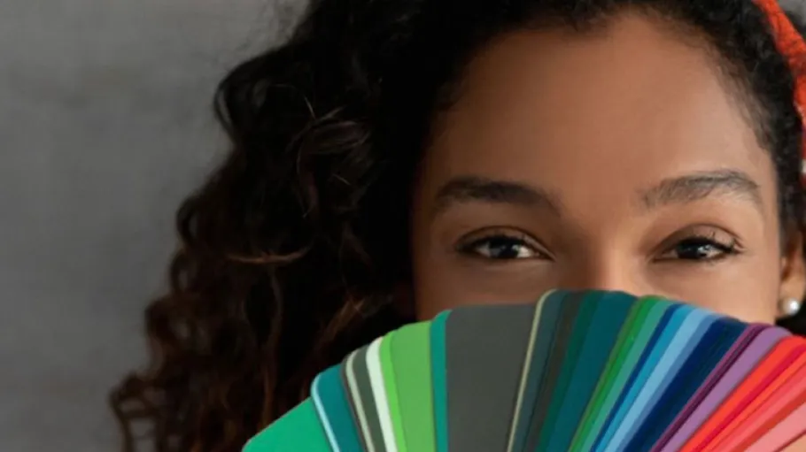 Person holding colorful paint swatches indoors.