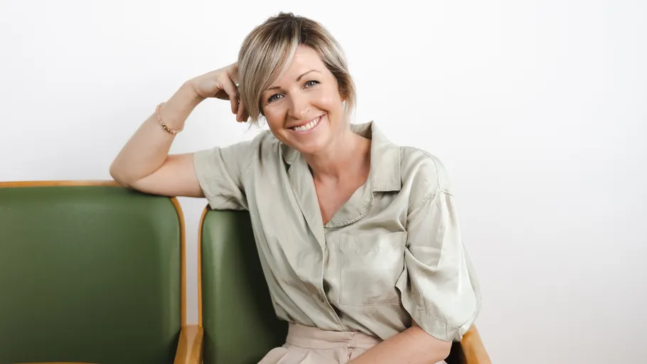 Smiling woman sitting on green chair indoors.