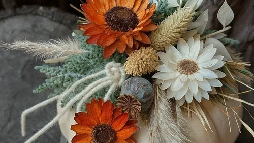 Herbstblumen auf einem weißen Kürbis arrangiert.