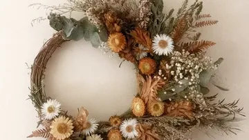 Blumenkranz mit Trockenblumen an Wand.