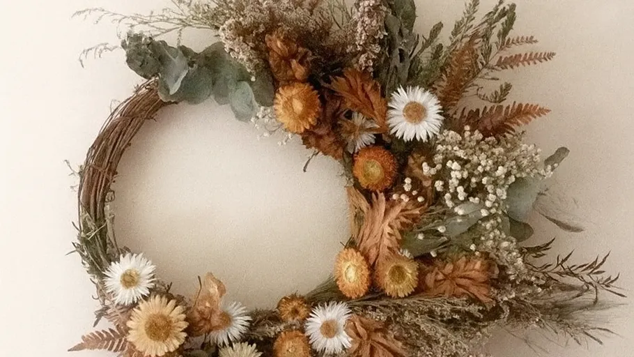 Blumenkranz mit Trockenblumen an Wand.