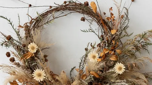 Rustikaler Kranz mit Trockenblumen an Wand.