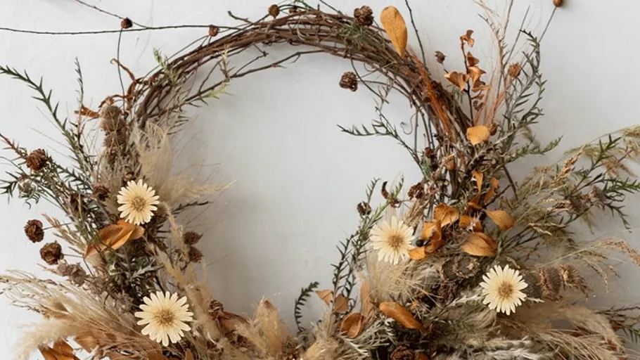 Rustic wreath with dried flowers on wall.