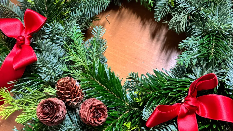 Festive wreath with red bows on table.