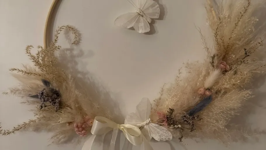 Dekorativer Kranz mit Trockenblumen und Schmetterling.