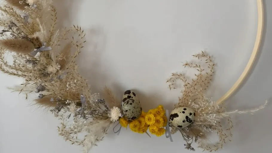 Dekorativer Kranz mit Trockenblumen und Eiern.