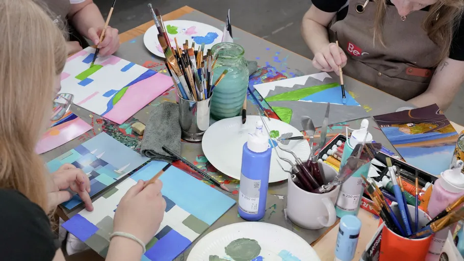 People painting on canvases at a table.