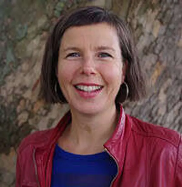 Smiling woman in red jacket outdoors.