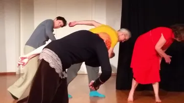 Four people bending in a dance rehearsal.