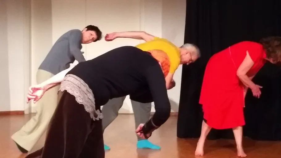 Four people bending in a dance rehearsal.