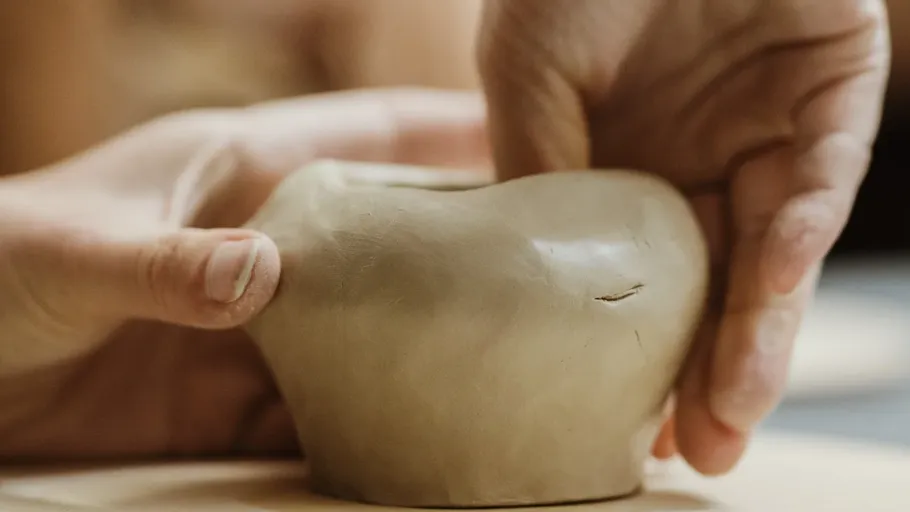 Hände formen Tonkeramik drinnen.