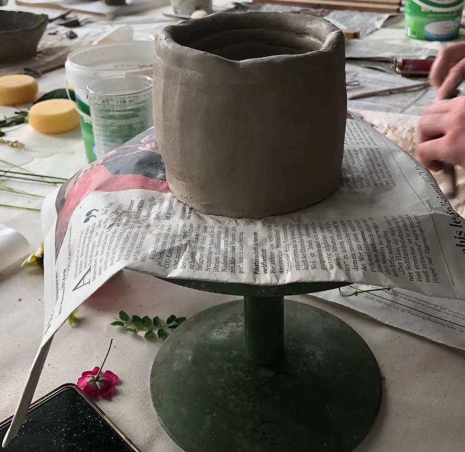 Clay pot on newspaper, pottery workspace.