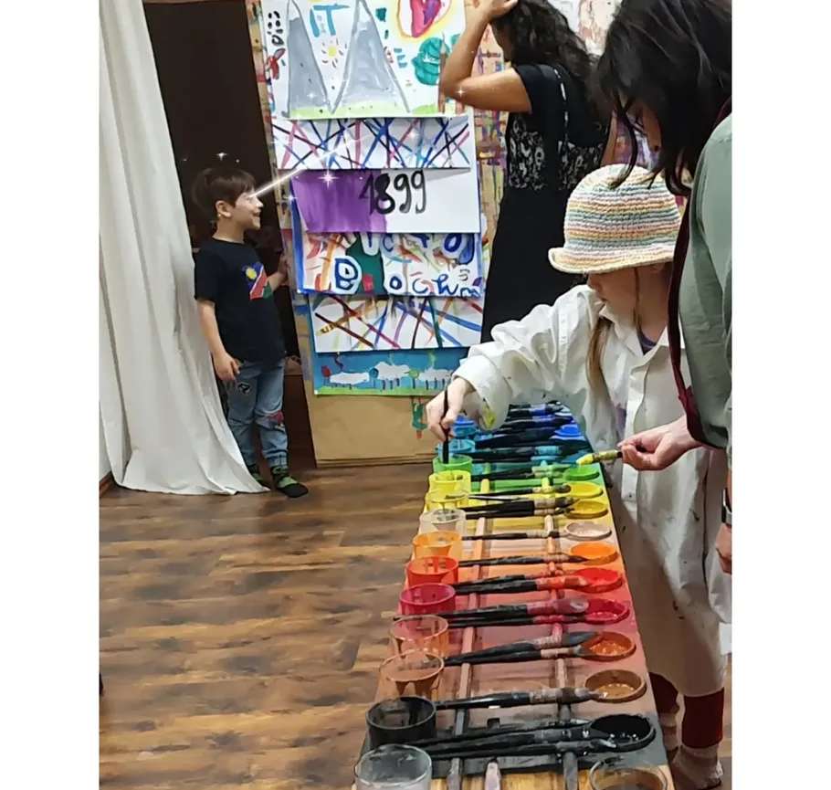 Kind malt mit bunten Farben im Klassenzimmer.