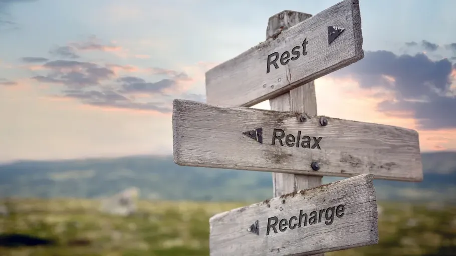 Wooden signs reading Rest, Relax, Recharge outdoors.