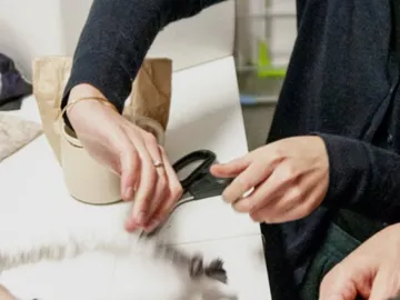 Schneider cuts material on a table in a room.