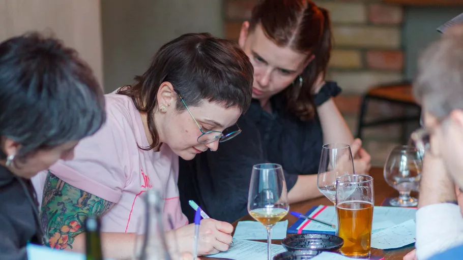 People writing at a table with drinks.