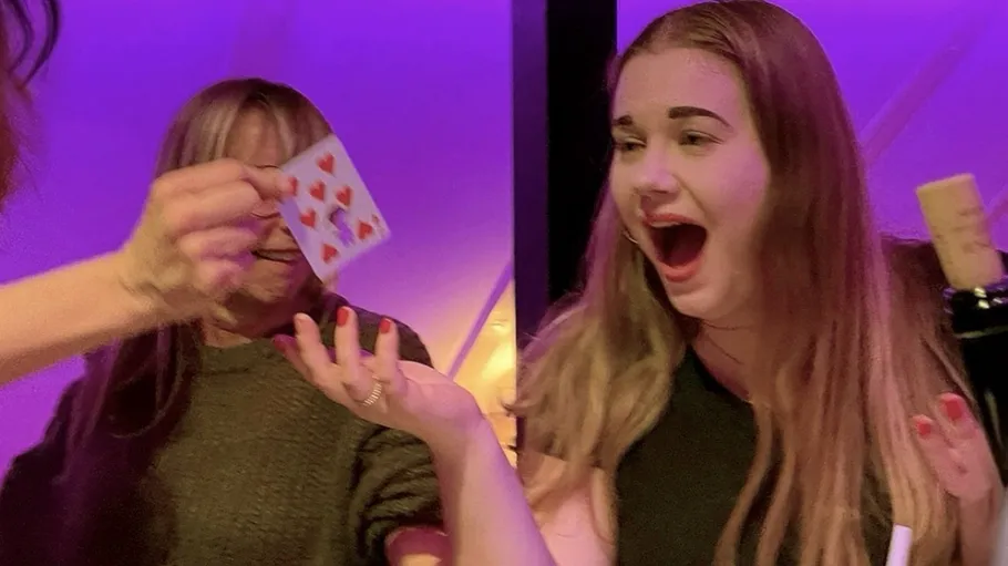 Excited woman reacts to playing card trick.