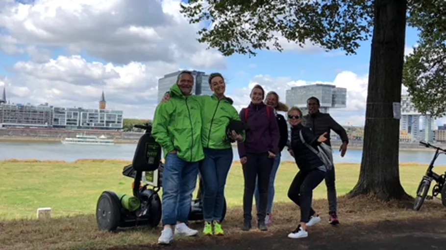 Gruppe posiert mit Segways unter einem Baum.
