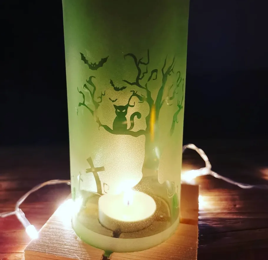Green candle holder with spooky Halloween design.