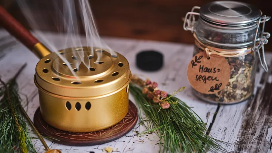 Incense burner with smoke beside glass jar.