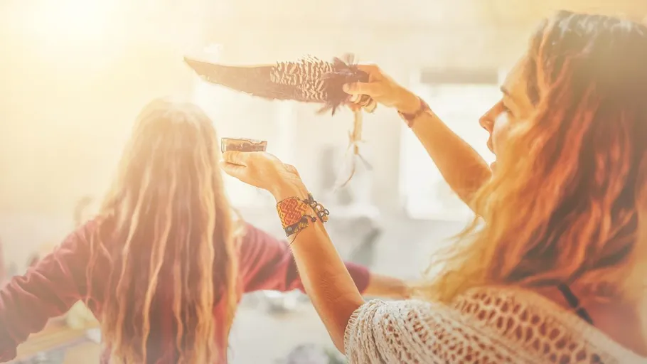 Woman holding feather and bowl in bright room.