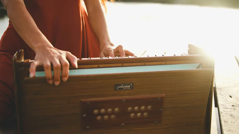 Person playing harmonium on a sunny day.
