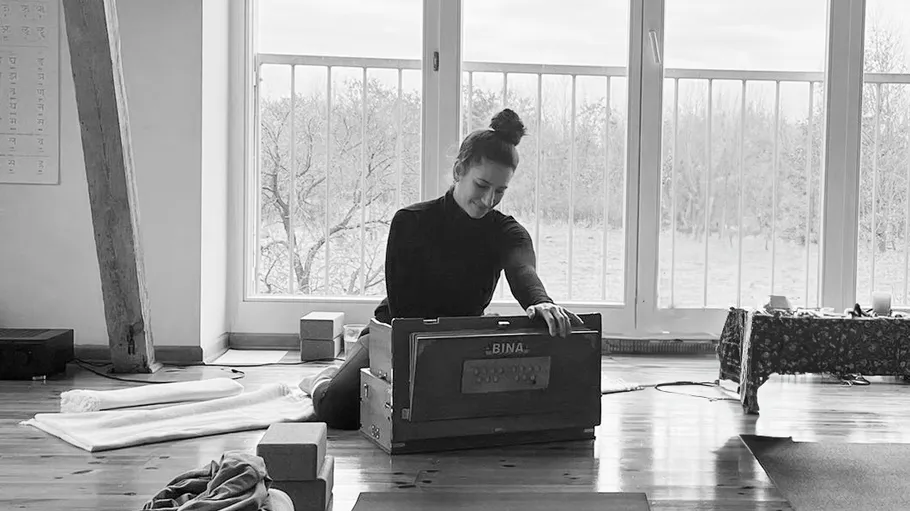 Person spielt Harmonium in hellem Raum.