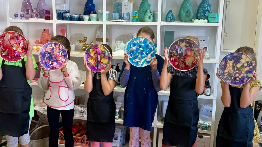 Kinder halten dekorierte Teller im Kunstraum.
