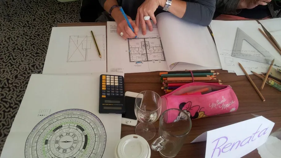 Person drawing floor plan with tools on table.