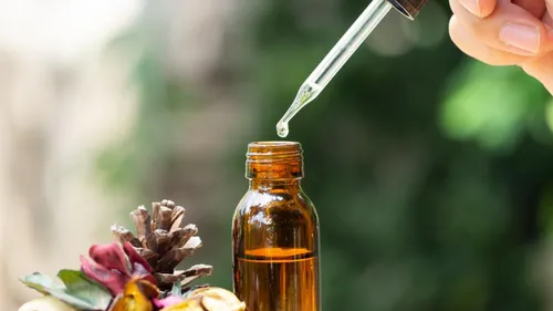 Pipette tropft Flüssigkeit in braune Flasche draußen.