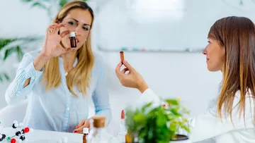 Two women examine bottles in a laboratory.