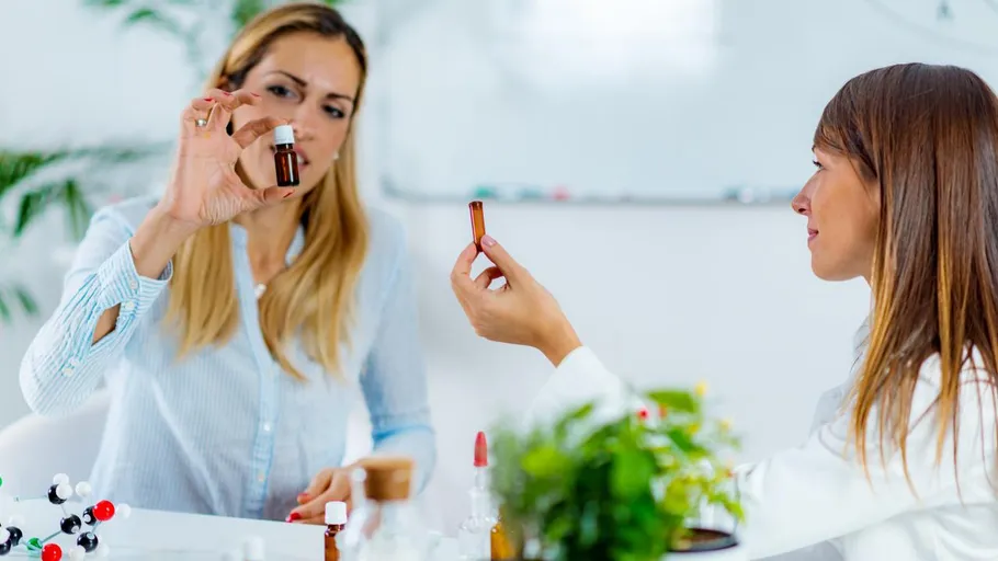 Two women examine bottles in a laboratory.