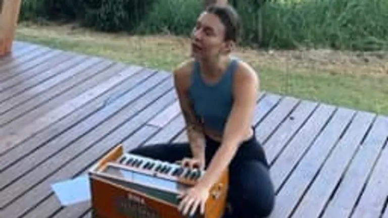 Person spielt Harmonium auf Holzterrasse im Freien.