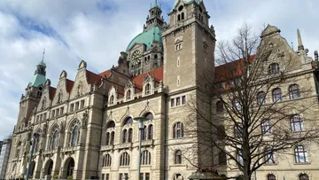 Historisches Gebäude mit Uhr, bewölkter Himmel.