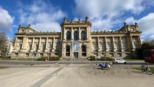 Historisches Gebäude mit verzierter Fassade und Wolkenhimmel.