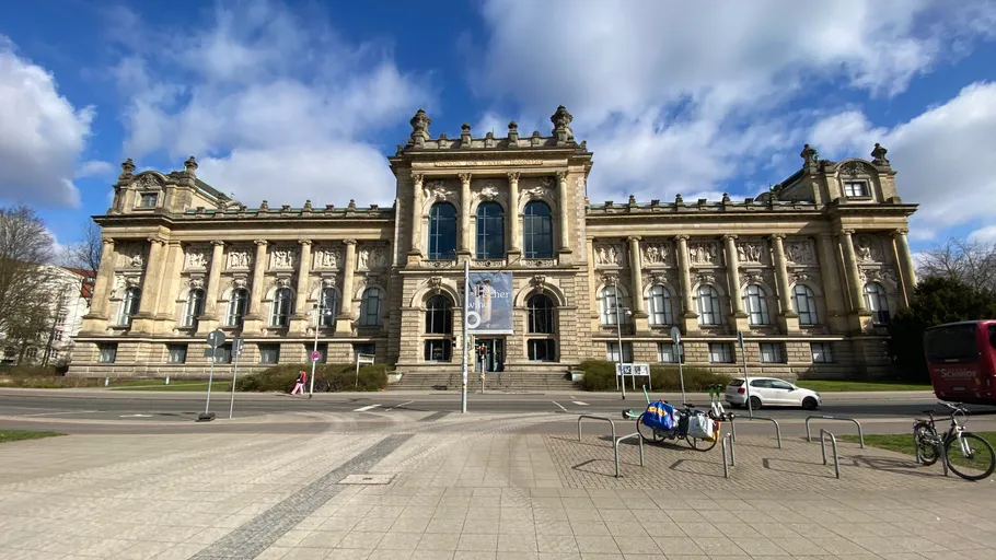 Historisches Gebäude mit verzierter Fassade und Wolkenhimmel.