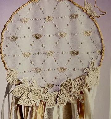Lace dreamcatcher with floral decorations, indoors.