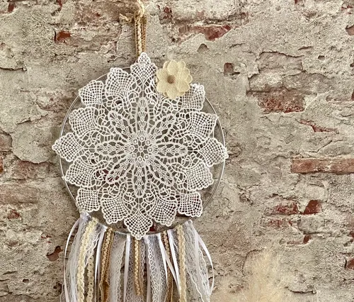 Lace dreamcatcher hanging on brick wall.