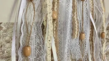 Spitze und Bänder mit Holzperlen hängen.