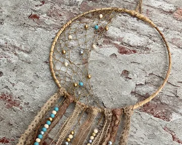 Dreamcatcher with beads hanging on brick wall.