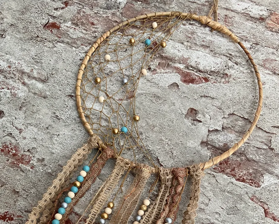Dreamcatcher with beads hanging on brick wall.