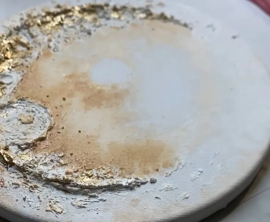 Texturierte Leinwand mit Gold- und Weißfarbe.
