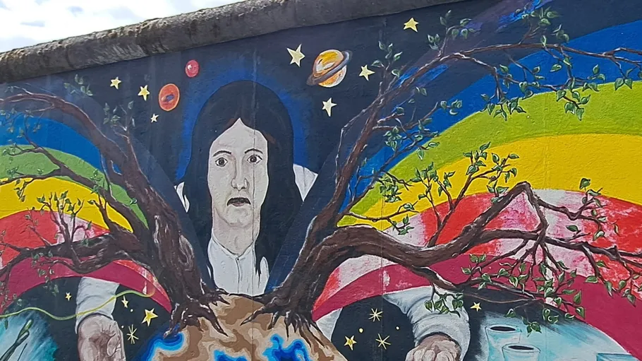 Mural of a face with tree branches, rainbow background.