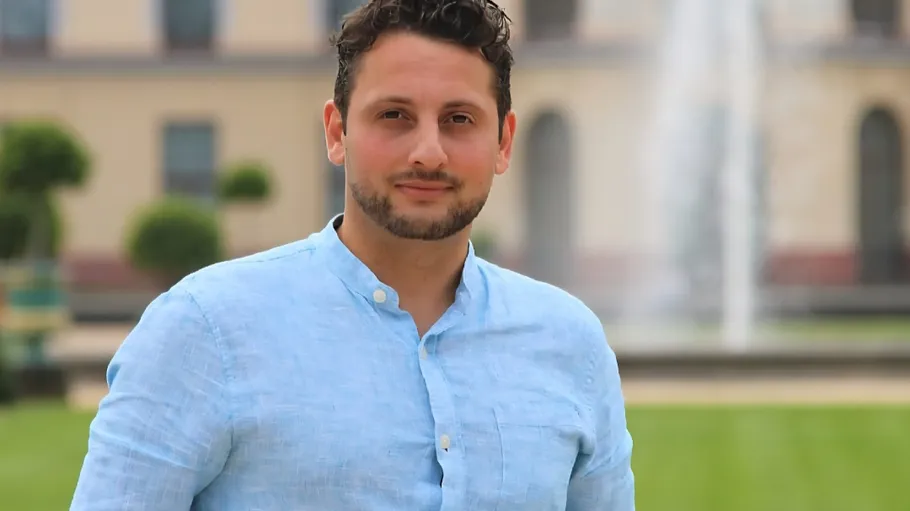 Man standing near fountain in garden.